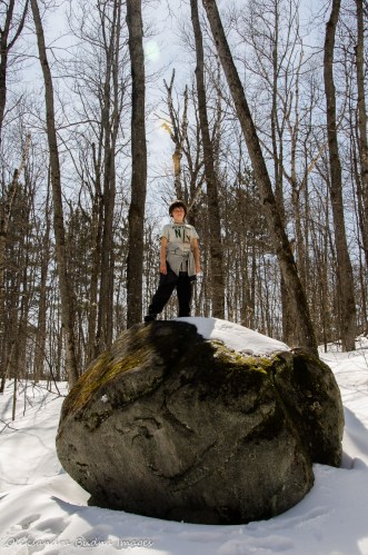 kid on a rock in the forest in the winter