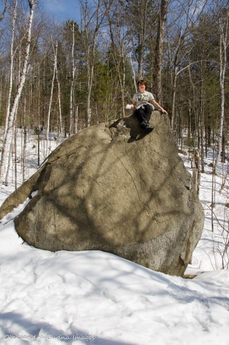 kid on a rock in the forest in the winter