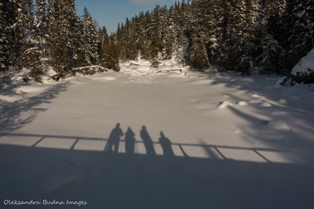 shadows of people on the bridge on the snow covered lake