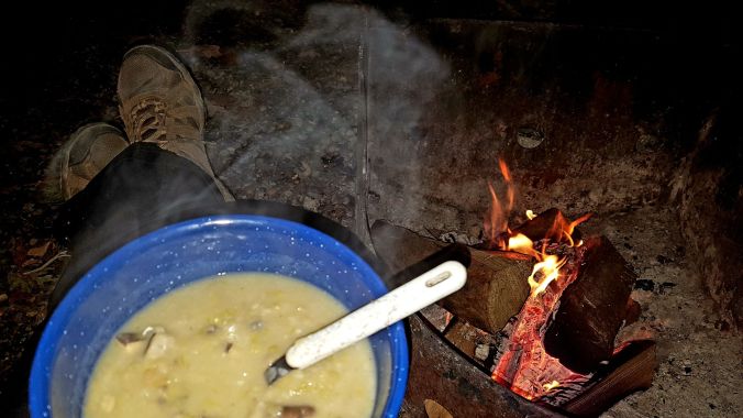 a bowl of soup in front of the campfire