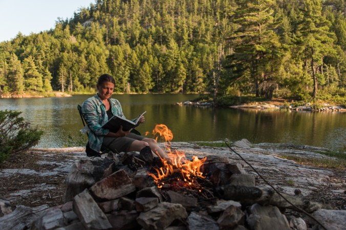 reading by the campfire on site 179 on Grace Lake in Killarney